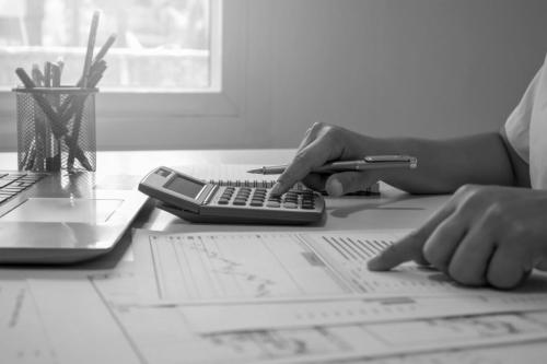 Close-up of businessmen or accountants holding a pen and pressing on the calculator to calculate business information, accounting documents, business ideas.